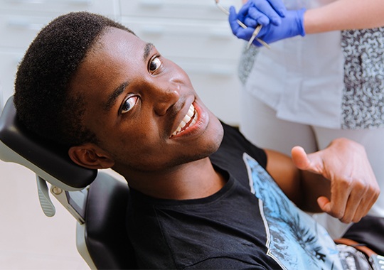 Young man in dental chair giving thumbs up