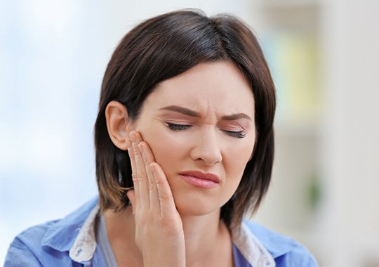 Woman in pain holding jaw