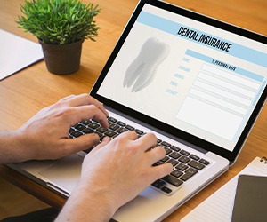Patient filling out dental insurance form on laptop