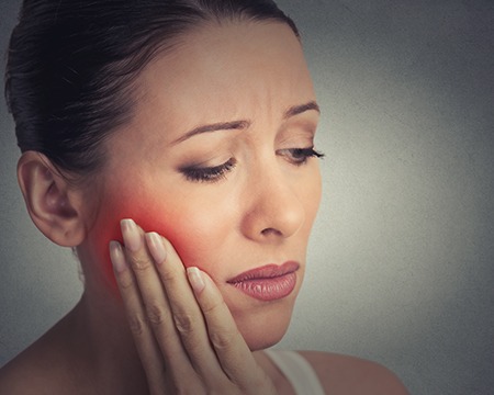 Woman holding cheek in pain