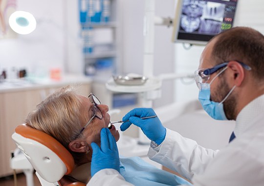 Dentist using tools to examine patient's teeth