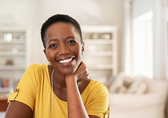 Woman in yellow shirt smiling in living room