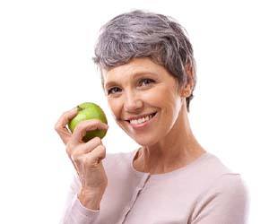 smiling woman holding a green apple