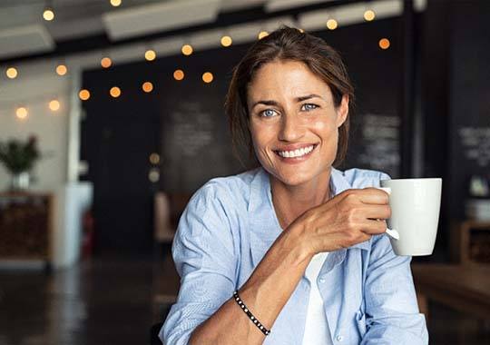 smiling woman holding a white coffee mug