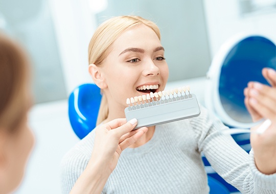 Woman's smile compared with tooth color chart