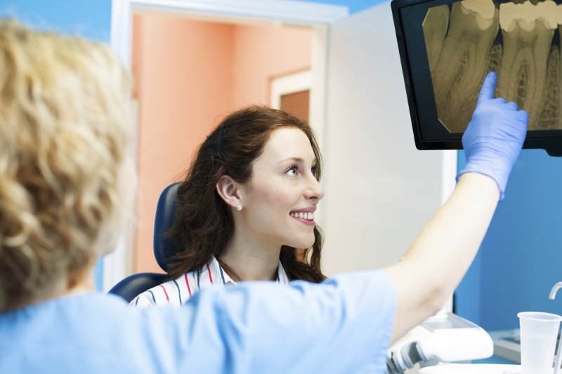 A dentist pointing at a dental X-ray for a patient.