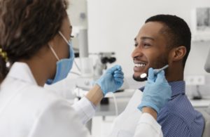 young man sitting in dental chair and smiling at his dentist in Hammonton