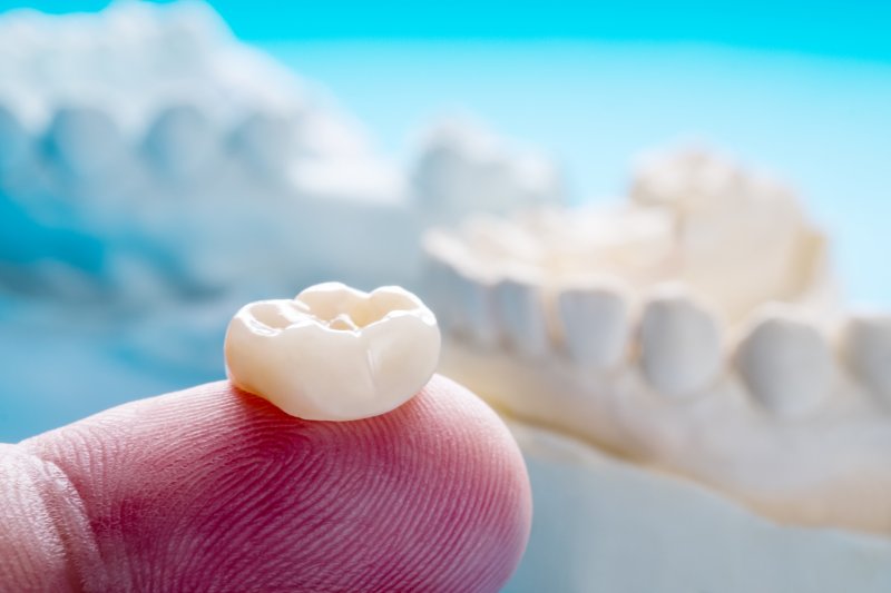 an up-close look at a person’s finger holding a customized dental crown