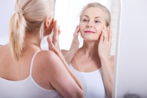 Older woman with teeth shifting looking in mirror