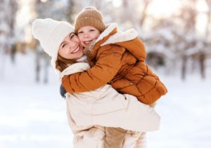 a mother and her child smiling and protecting their smiles during the winter 